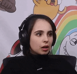 a woman wearing headphones is sitting in front of a cartoon rainbow .