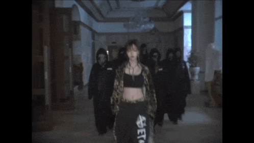 a woman in a leopard print jacket stands in a hallway surrounded by people wearing masks