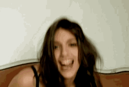 a woman in a black bra is smiling with her mouth open .