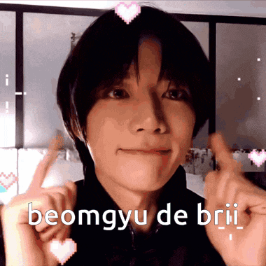a young man is making a heart shape with his hands and the words beomgyu de brii are written above him