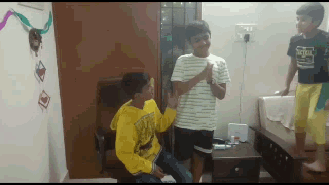a boy wearing a shirt that says tactical is standing next to two other boys