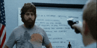 a man with a beard stands in front of a white board