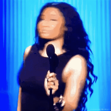 a woman in a black dress is holding a microphone in front of a blue background .