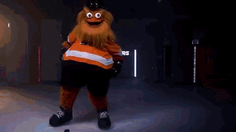 a mascot is standing on a ice rink with a puck in his hand .