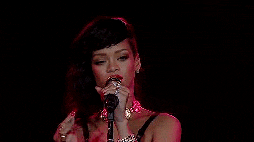 a woman is singing into a microphone on stage .