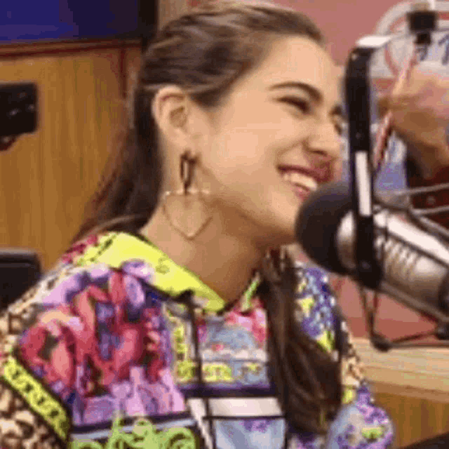 a woman is smiling in front of a microphone while wearing earrings .