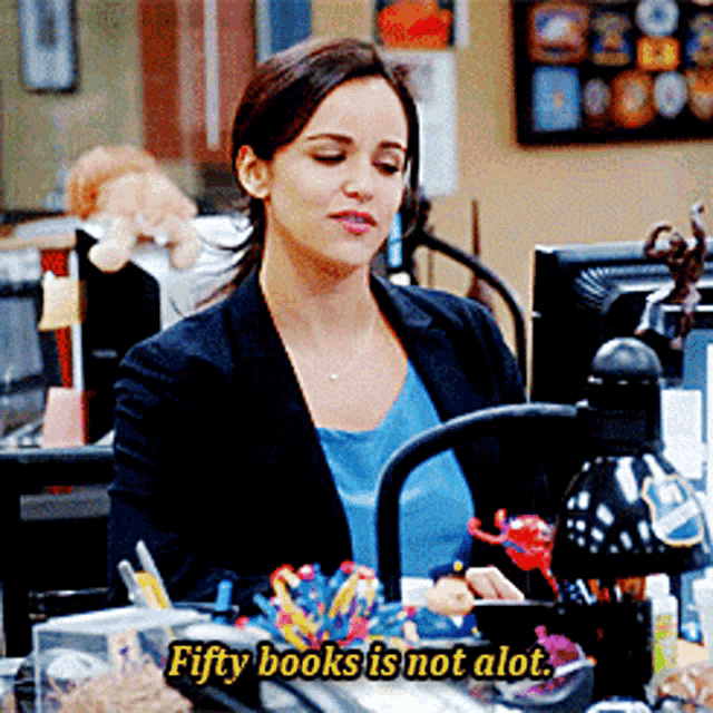 a woman sitting at a desk with the words fifty books is not alot below her