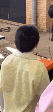 a boy in a yellow shirt is sitting in front of an orange amplifier