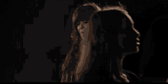 a woman with long red hair is talking to another woman in the dark
