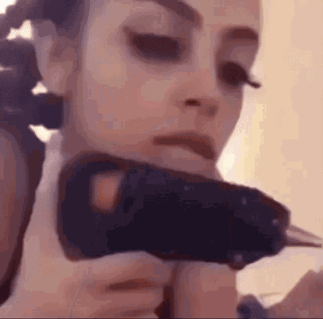 a close up of a woman holding a glue gun in her mouth .