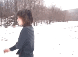 a woman in a striped shirt walking in the snow