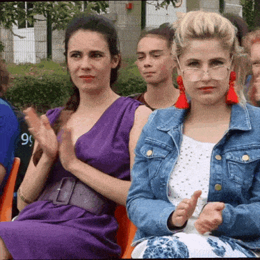 a woman in a purple dress sits next to a woman in a blue jacket