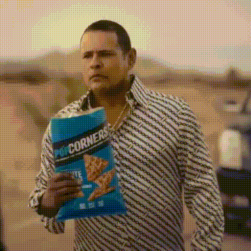 a man is holding a bag of popcorn and a bag of chips .
