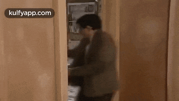 mr bean is standing in front of a door with a green balloon on it .