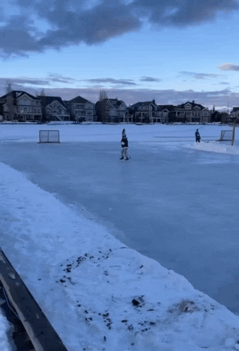 people playing ice hockey on a frozen lake in a residential area