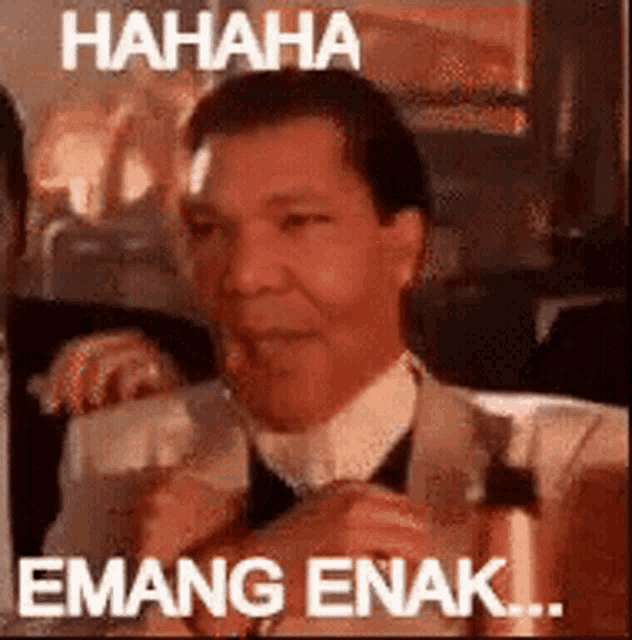 a man in a suit and tie is laughing with a caption that says `` hahaha emang enak '' .