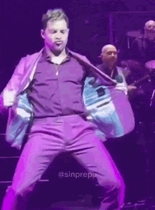 a man wearing purple pants and a purple shirt is dancing on a stage .