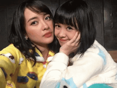 two girls are posing for a picture with one wearing a yellow shirt that says elmo