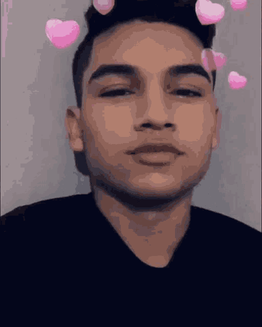 a young man wearing a black shirt with pink hearts on his head