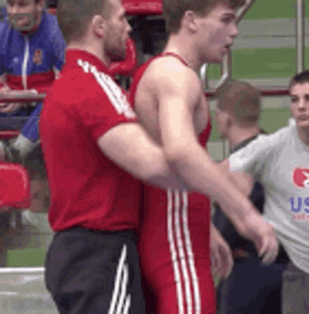 a man in a red shirt is shaking hands with another man in a white shirt .