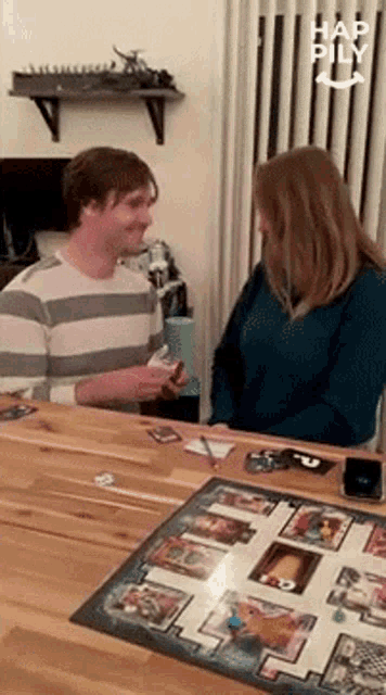 a man and a woman are playing a board game with hap pily in the background