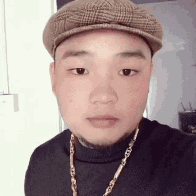 a man wearing a hat and a necklace is making a face .