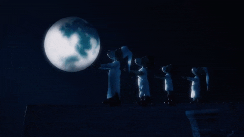 a group of people standing in front of a full moon in the dark
