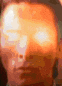 a close up of a man 's face with a glowing light coming out of his eyes