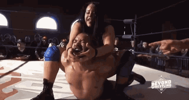 a woman is wrestling a man in a wrestling ring with the words beyond wrestling on the bottom .