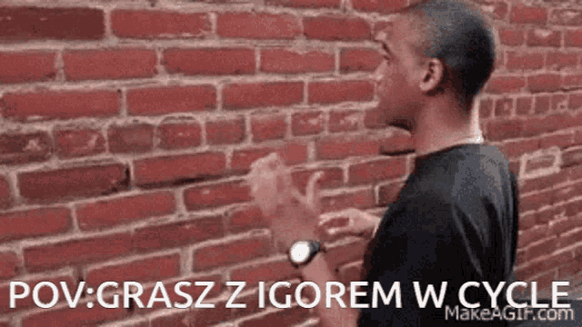 a man standing in front of a brick wall with the words pov grasz z igorem w cycle