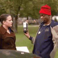 a man wearing a red hat is talking to a woman while holding a cell phone .