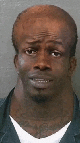 a man with a very long neck and a tattoo on his neck is looking at the camera .