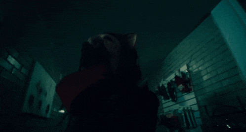 a woman in a hooded top is laying down in a dark room
