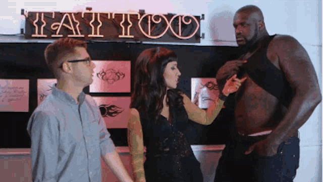 a man and a woman are standing in front of a tattoo shop