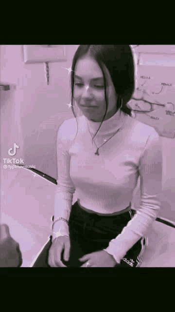 a black and white photo of a girl wearing a white turtleneck sweater and black pants .