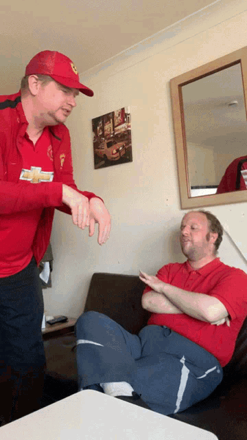 a man wearing a red chevrolet shirt is talking to another man in a red shirt