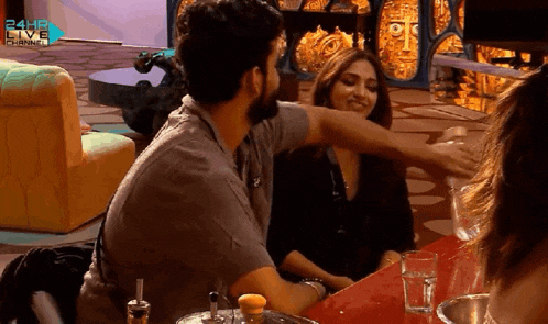 a man and a woman are sitting at a table in front of a 24hr live channel