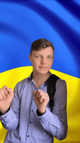 a young man wearing a backpack stands in front of a blue and yellow flag
