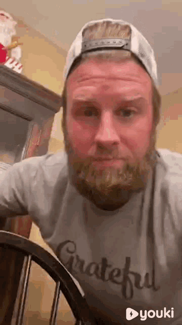 a man with a beard is wearing a hat and a grateful shirt .