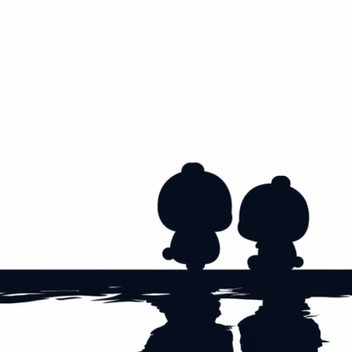 a couple of teddy bears sitting next to each other in front of a heart shaped light