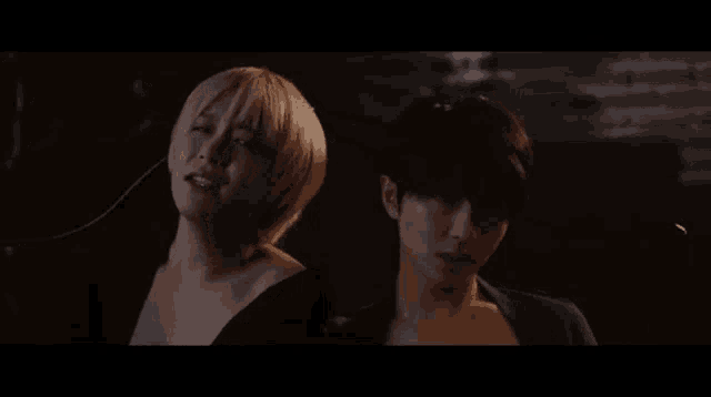 a man and a woman are standing next to each other in the dark