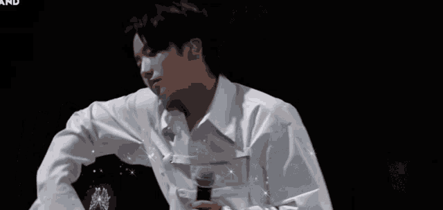 a man in a white shirt is dancing on a stage with his arms outstretched .