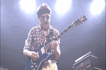 a man in a leopard print shirt plays a blue guitar