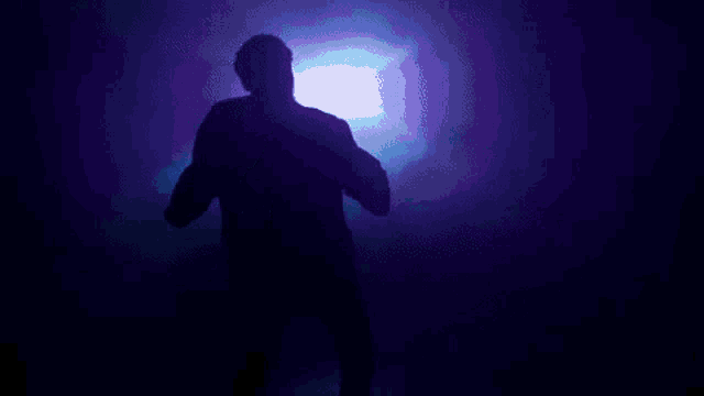 a silhouette of a man dancing in a dark room .