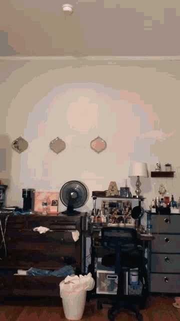 a messy room with a fan and a dresser