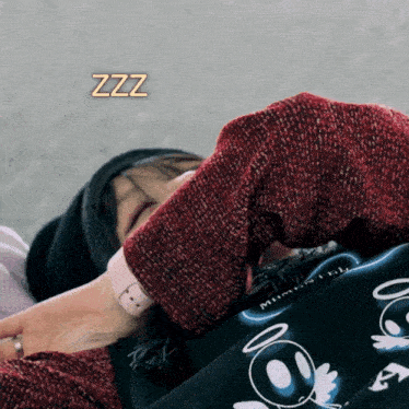 a person wearing a red sweater is sleeping with the word zzz above her