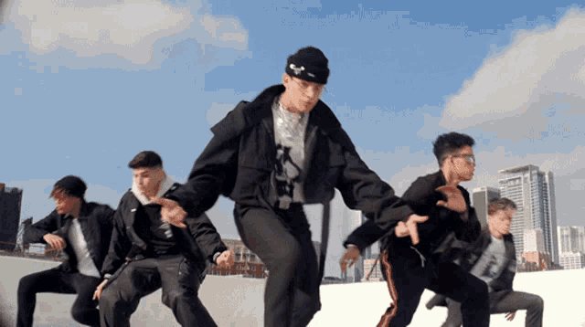 a group of young men are dancing in front of a skyline