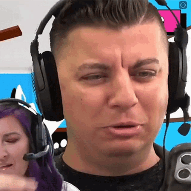 a man wearing headphones and a microphone is making a face .