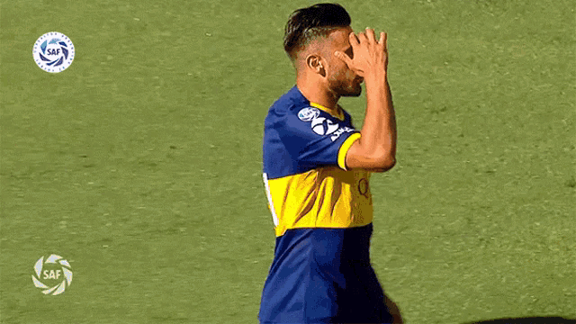 a man in a blue and yellow axion jersey stands on a field