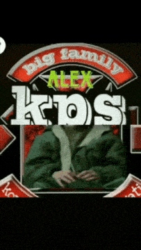 a man in a green jacket sits in front of a sign that says alex kos